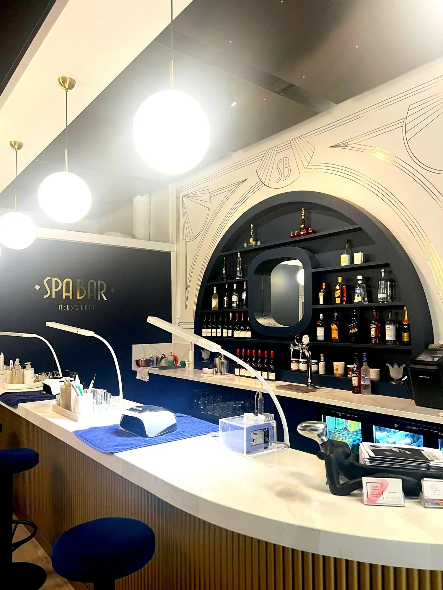 Spa Bar Melbourne — gold Art Deco lettering, navy walls and a curved marble manicure bar